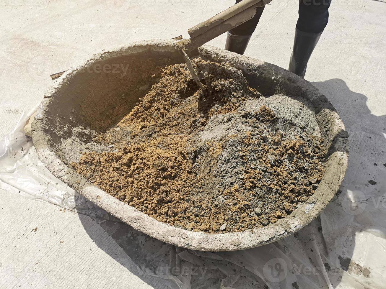 los trabajadores usan cemento húmedo para mezclar palas en el lavabo de mezcla de cemento, enfoque selectivo foto