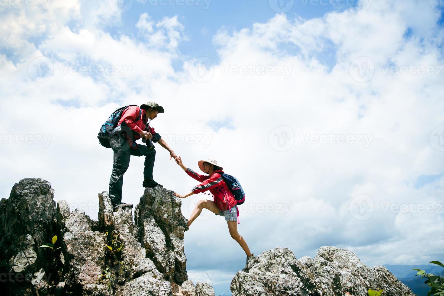 Person hike friends helping each other up a mountain. Man and woman giving a helping hand and active fit lifestyle. Asia couple hiking help each other. concept of mentor friendship, teamwork. photo