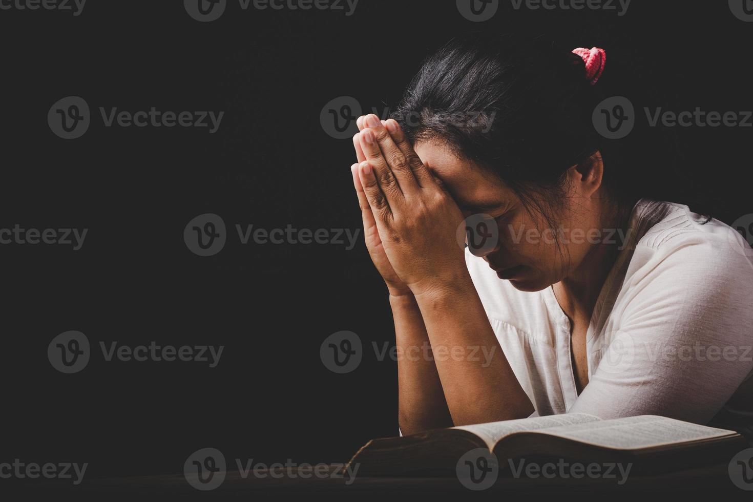 christian woman hand on holy bible are pray and worship for thank god in church with black background, concept for faith, spirituality and religion photo