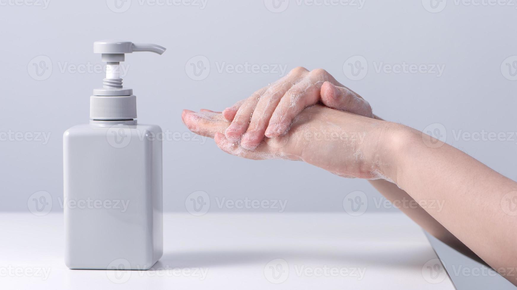 Washing hands. Asian young woman using liquid soap to wash hands, concept of hygiene to protective pandemic coronavirus isolated on gray white background, close up. photo