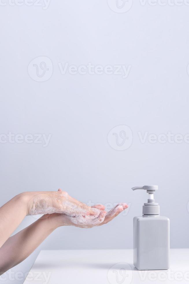 Washing hands. Asian young woman using liquid soap to wash hands, concept of hygiene to protective pandemic coronavirus isolated on gray white background, close up. photo