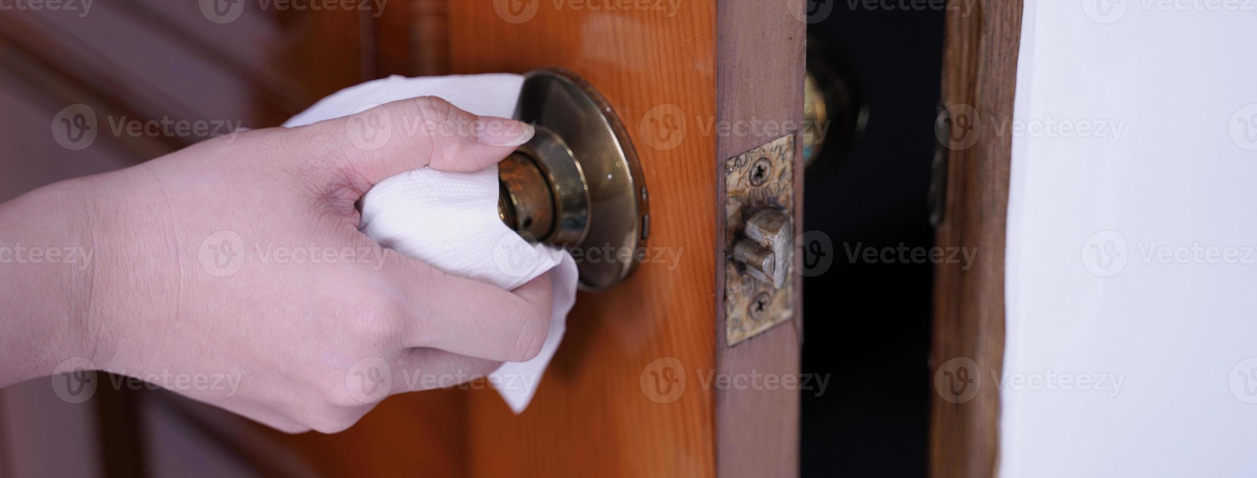 Young Asian woman adult opening door with clean tissue on the knob handle instead of hand, concept of antibacterial, virus prevention, close up. photo