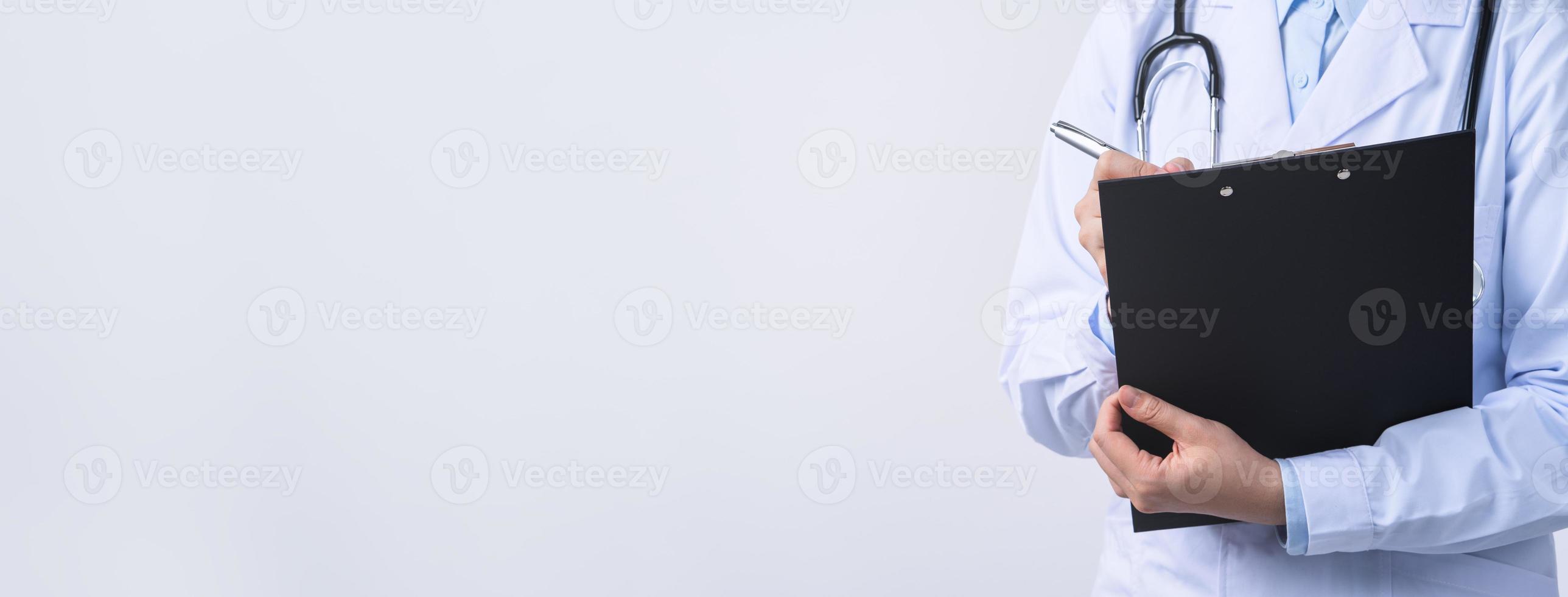 Doctor with stethoscope in white coat holding clipboard, writing medical record diagnosis, isolated on white background, close up, cropped view. photo