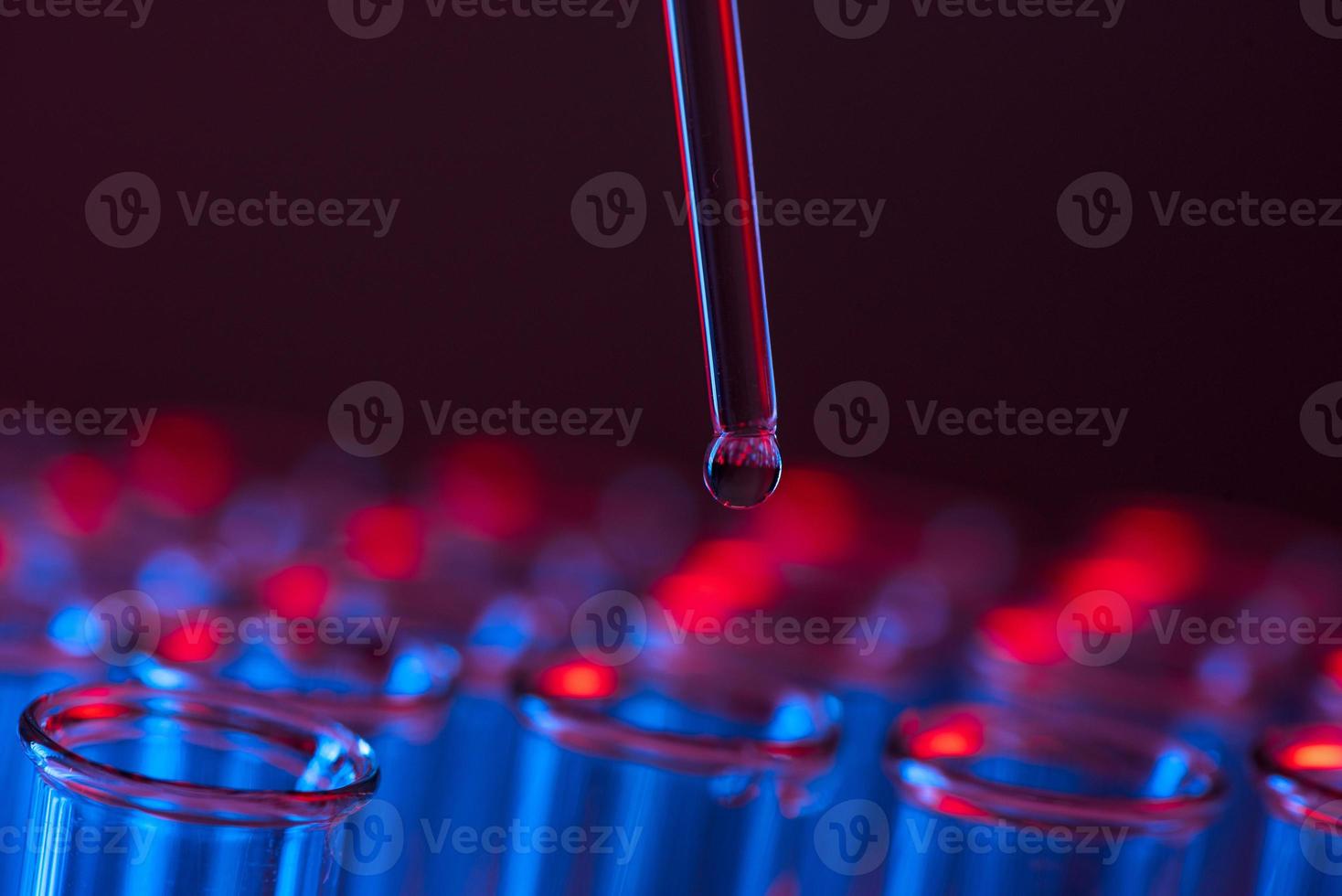 Test tube row. Concept of medical or science laboratory, liquid drop droplet with dropper in blue red tone background, close up, macro photography picture. photo