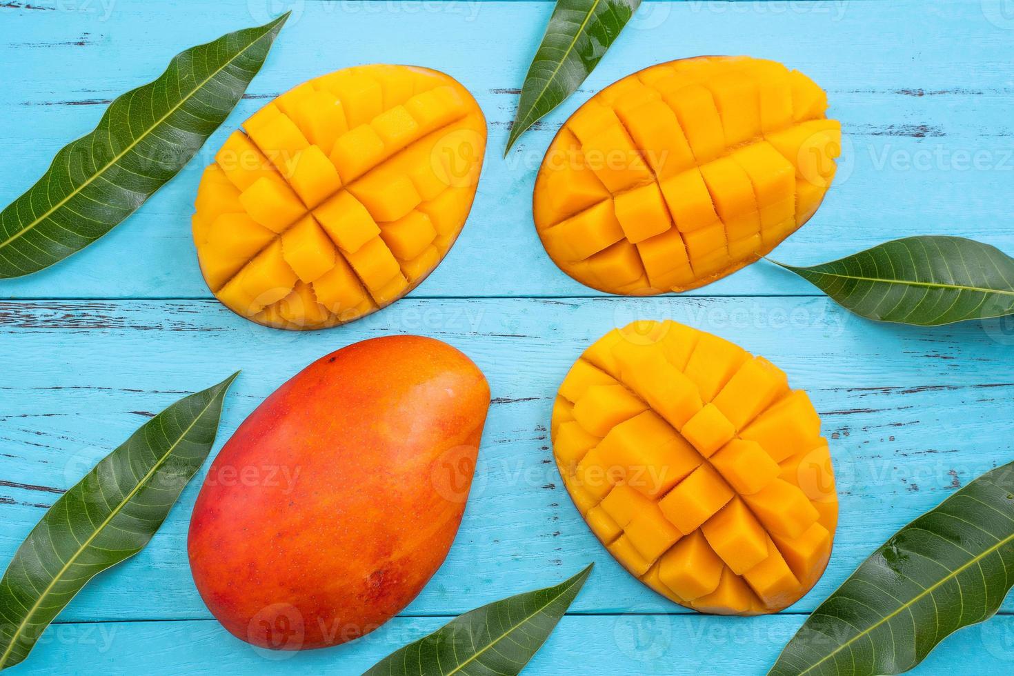 Mango - Fresh chopped tropical mango fruit isolated on bright vibrant light blue wooden table background, top view, flat lay layout, overhead shot. photo