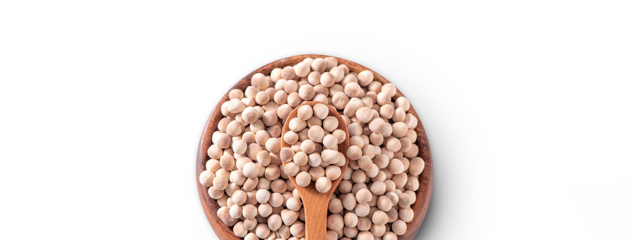 Dry raw brown tapioca pearls in a wooden bowl with spoon isolated on white background, close up, ingredient of making bubble boba milk tea. photo