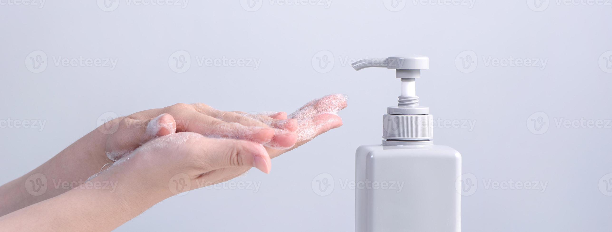 Washing hands. Asian young woman using liquid soap to wash hands, concept of hygiene to protective pandemic coronavirus isolated on gray white background, close up. photo