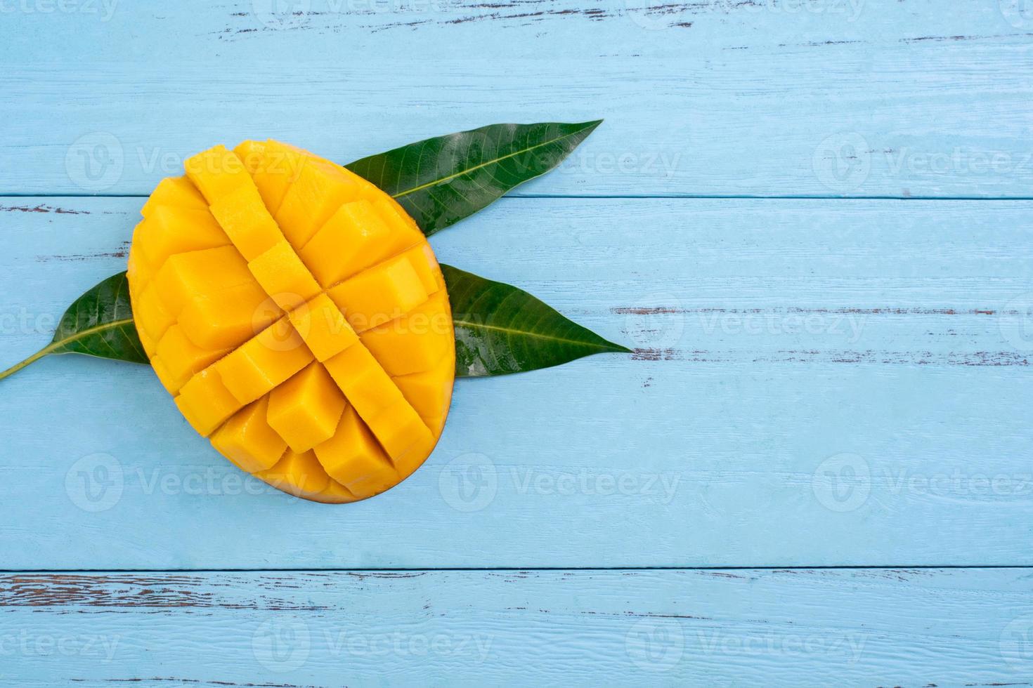 Mango - Fresh chopped tropical mango fruit isolated on bright vibrant light blue wooden table background, top view, flat lay layout, overhead shot. photo