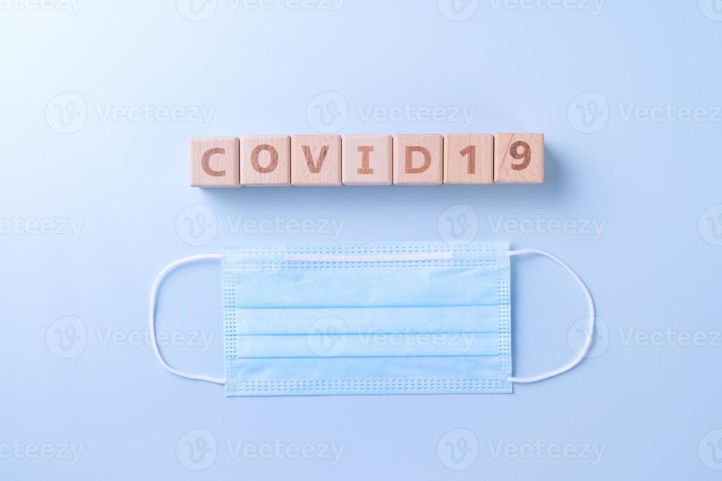 COVID-19 word wooden cube with mask, medical equipment, world disease pandemic infection and prevention concept, top view, flat lay, overhead design photo