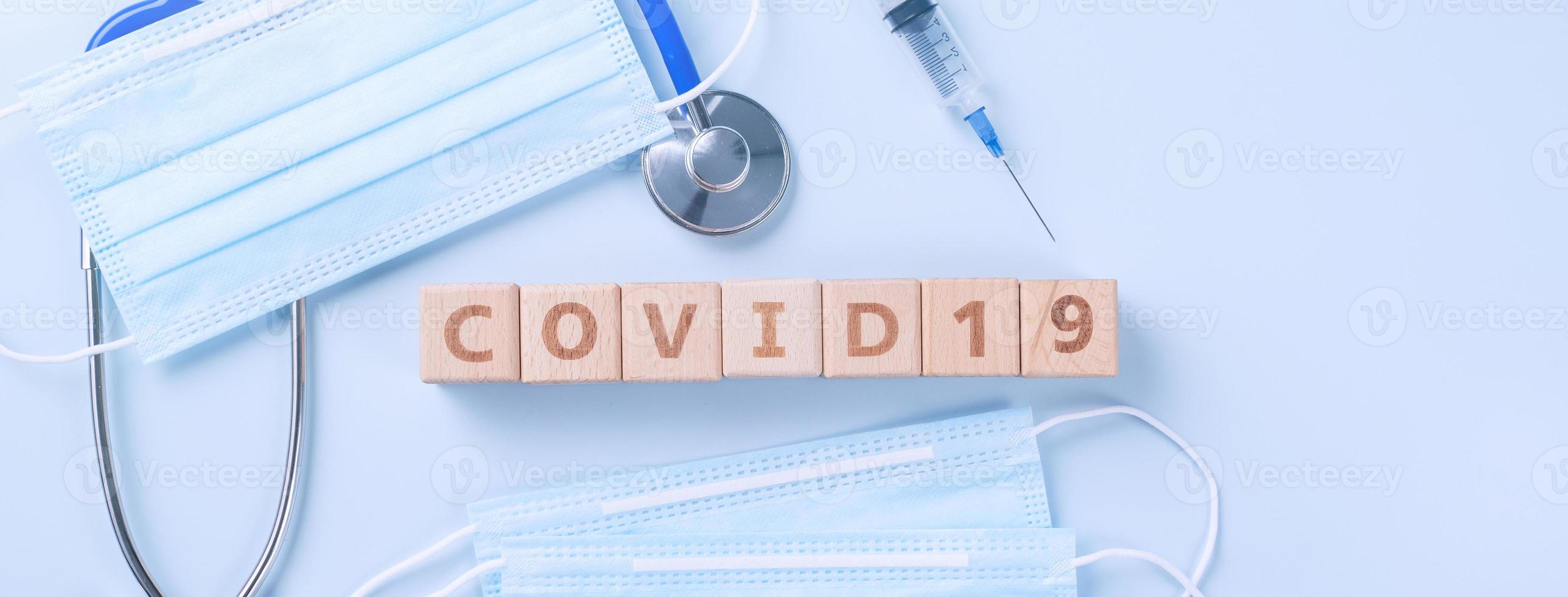 COVID-19 word wooden cube with mask, medical equipment, world disease pandemic infection and prevention concept, top view, flat lay, overhead design photo