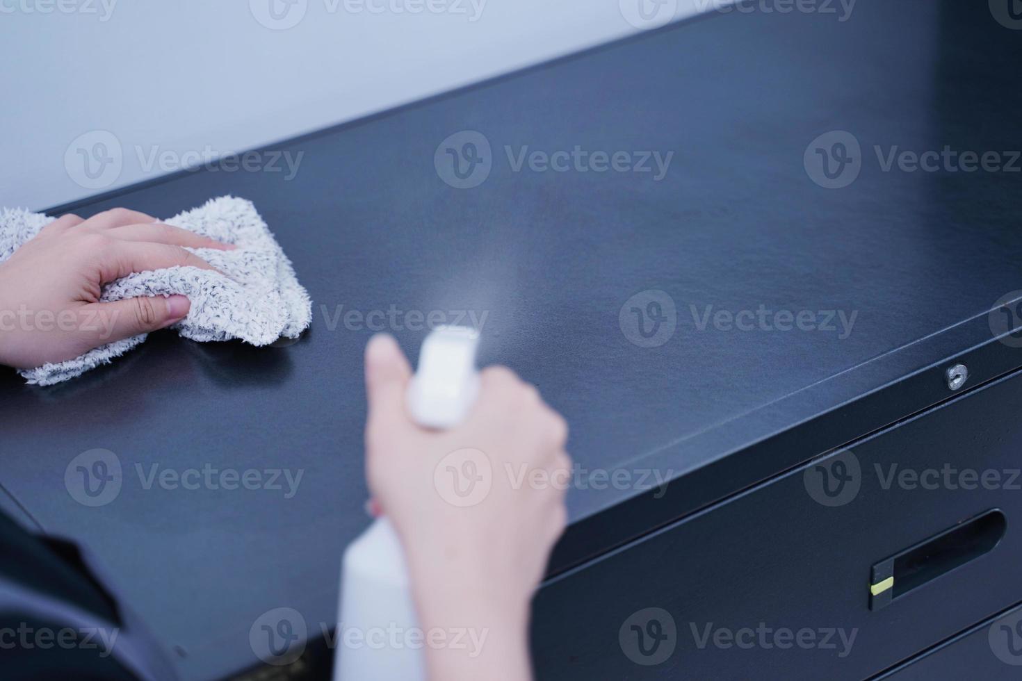 Young woman is holding spray bottle, rag to clean, wipe down office metal cabinet shelf accommodation surface, close up, lifestyle, concept of antibacterial. photo