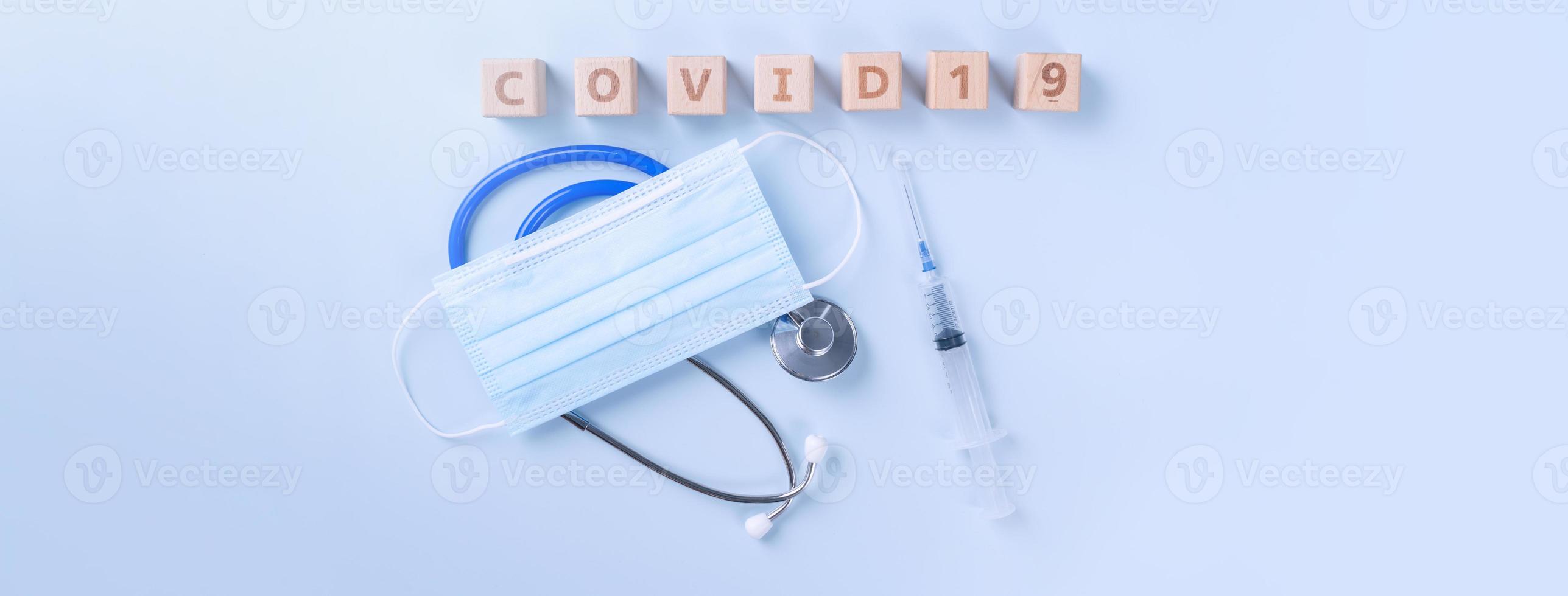 COVID-19 word wooden cube with mask, medical equipment, world disease pandemic infection and prevention concept, top view, flat lay, overhead design photo