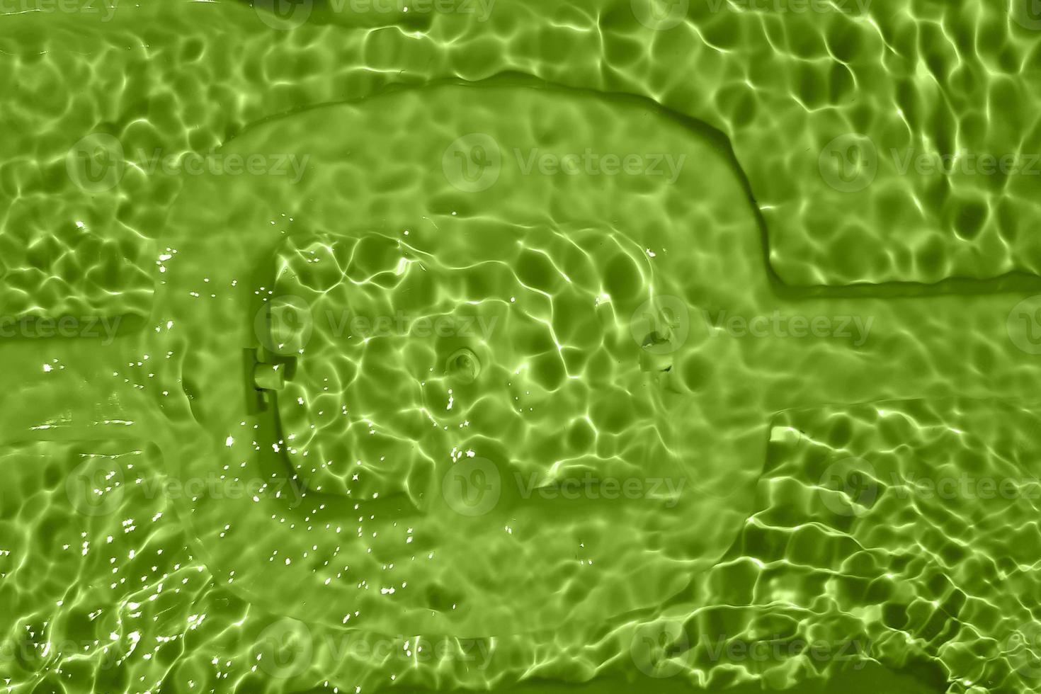 Defocus blurred transparent green colored clear calm water surface texture with splash, bubble. Shining green water ripple background. Surface of water in swimming pool. Tropical green water textures. photo