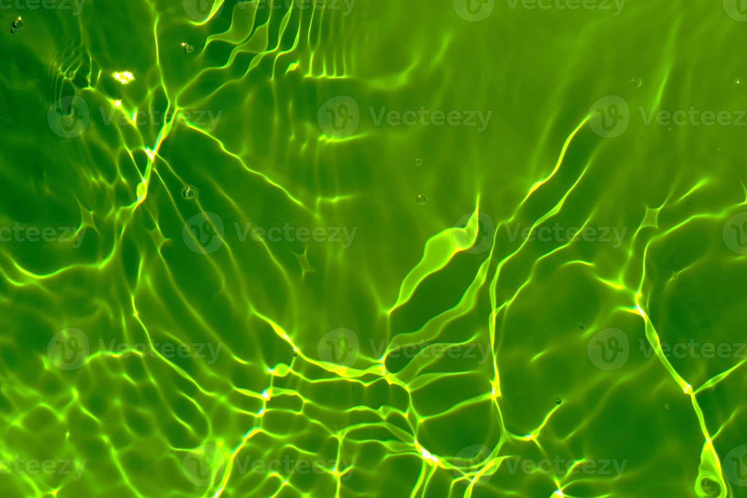 Defocus blurred transparent green colored clear calm water surface texture with splash, bubble. Shining green water ripple background. Surface of water in swimming pool. Tropical green water textures. photo