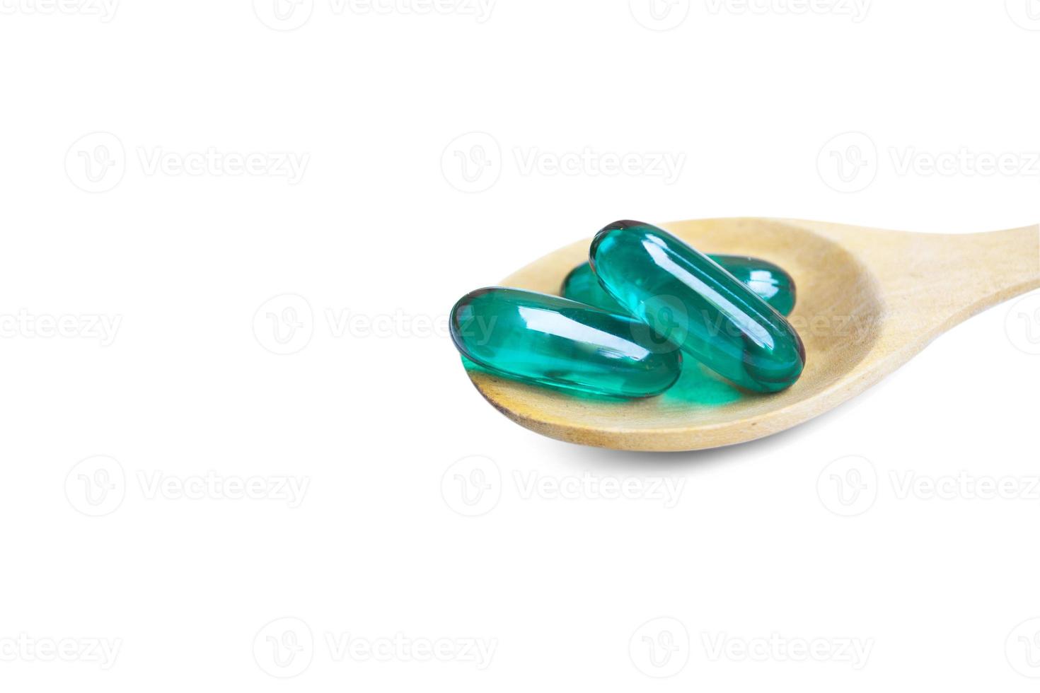 Aqua blue soft capsules on wooden spoon isolated on white background.File contains a clipping path. photo