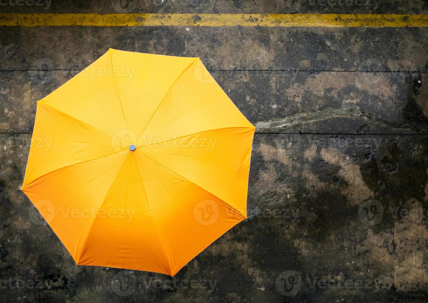 An orange umbrella on rainy day on wet congrete background .Top view photo