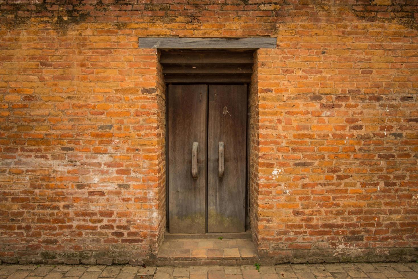 la pared de ladrillo naranja y la puerta vieja en medio de la pared en katmandú, nepal. foto