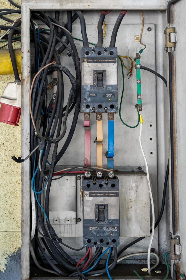 Gabinete de acero de interruptor eléctrico trifásico peligroso de 220v. el cableado no está ordenado, la caja de conexión de alimentación está unida a la pared de cemento externa. foto