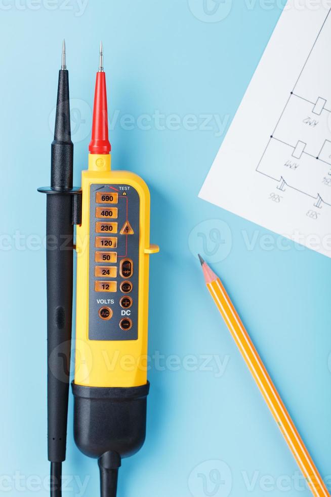 Two-pole voltage indicator with electrical drawings on a blue background. photo