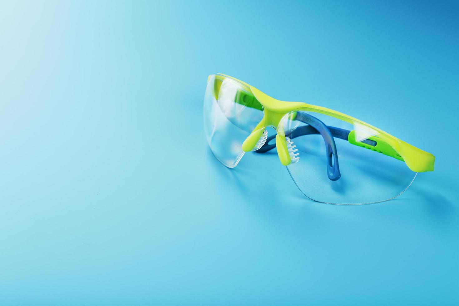 Technological protective green glasses isolated on a blue background. photo