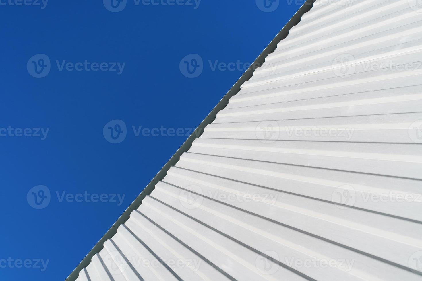 Geometry of a white corrugated metal building against a blue sky. photo