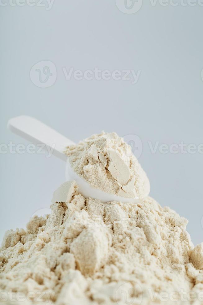 Whey protein isolate with a measuring spoon on a white background. photo