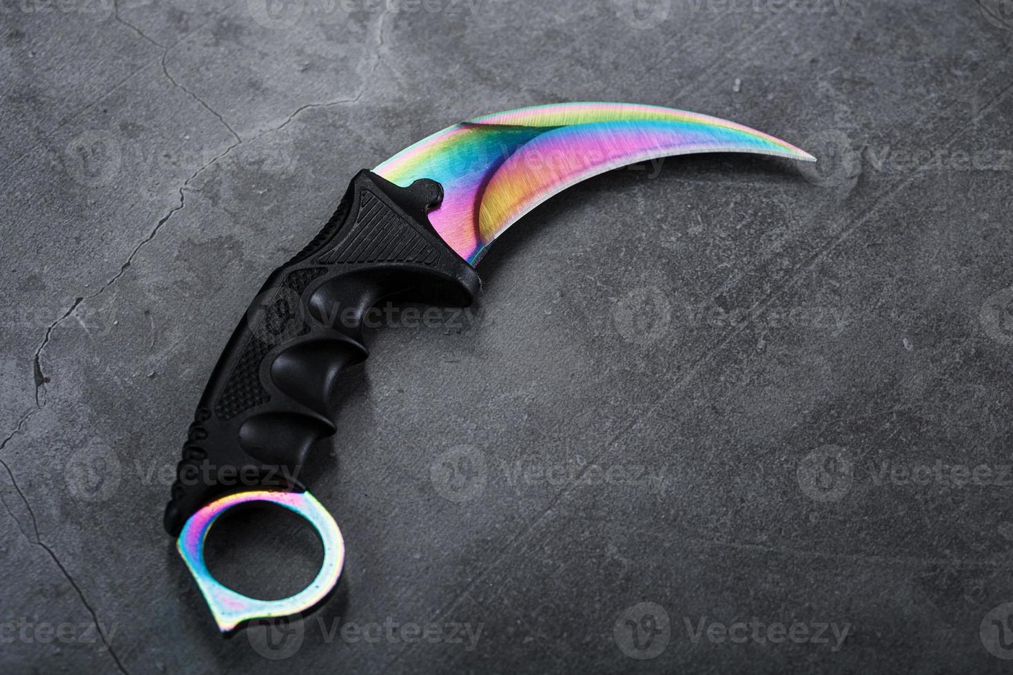 A dagger with a steel blade with a gradient color on a black background. photo