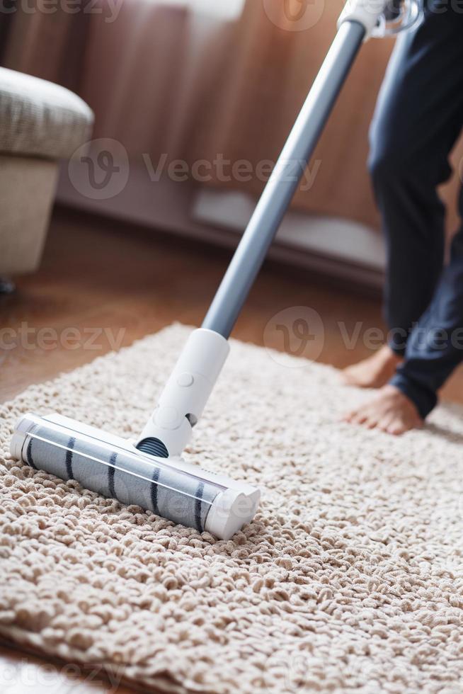 The turbo brush of a cordless vacuum cleaner cleans the carpet in the house in close-up photo