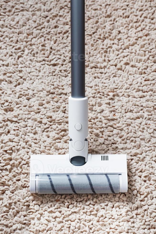 A white turbo brush of a cordless vacuum cleaner on the carpet. Indoor cleaning concept photo