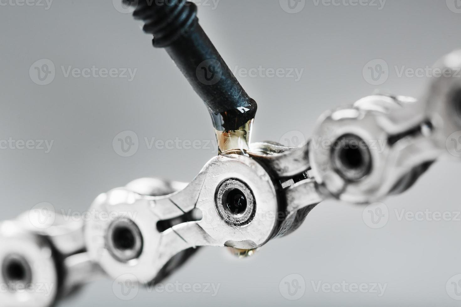 Greasing a bicycle chain with a drop of golden oil close-up on a gray background photo