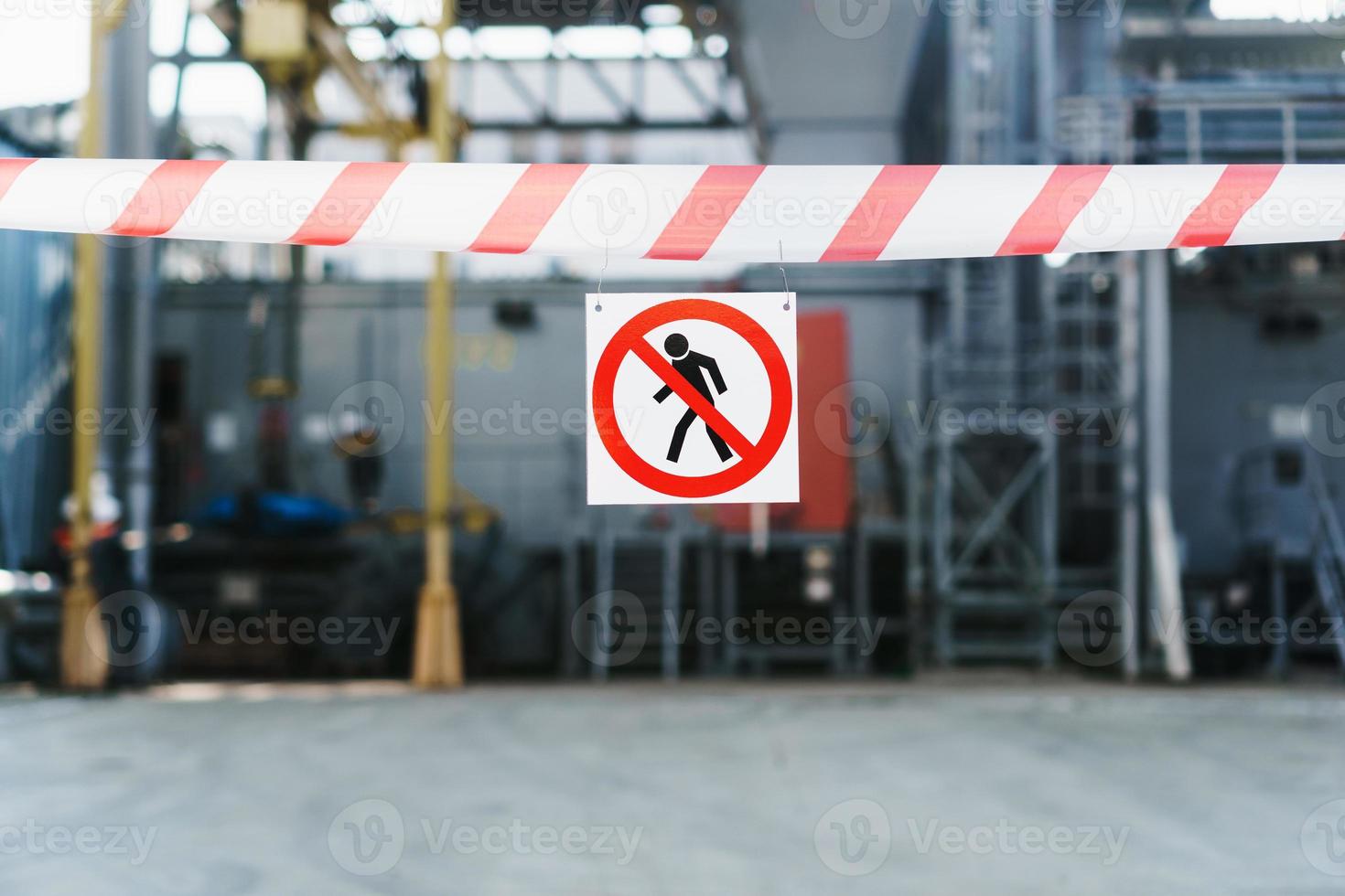 el cartel no se permite el paso en una cinta roja y blanca que cerca el pasaje contra el fondo de las tuberías de la planta de energía. foto