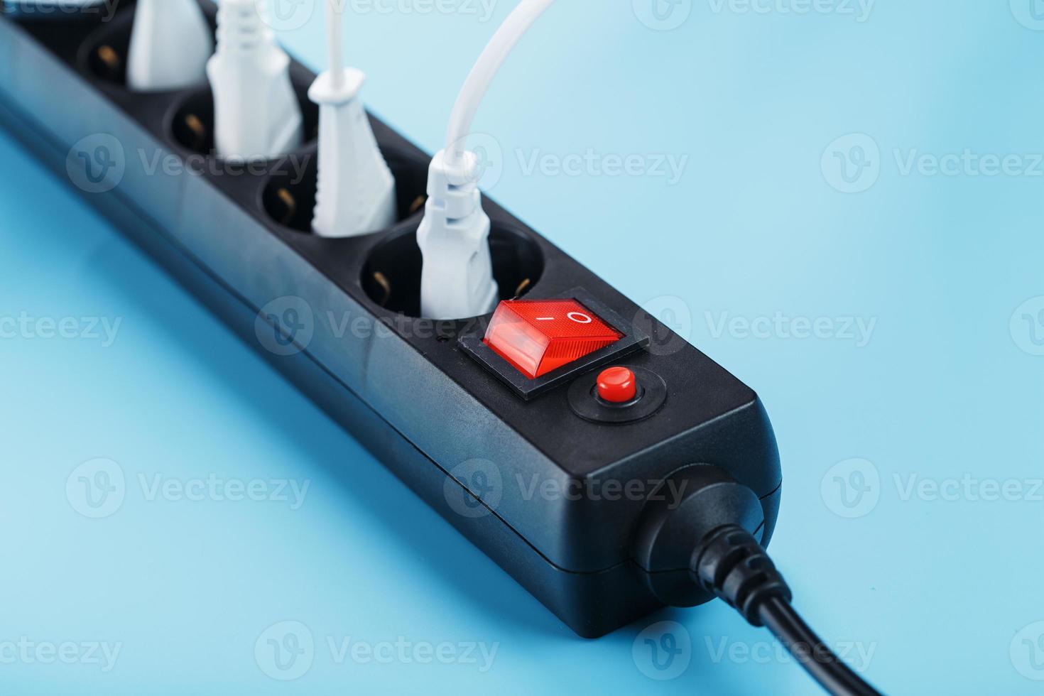 Electric mains filter with inserted white plugs of electrical appliances on a blue background. photo