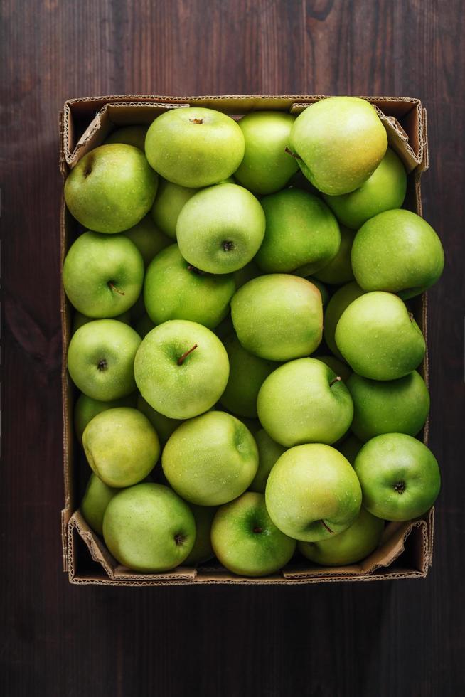 manzanas verdes maduras y jugosas en una caja sobre una mesa de madera. foto