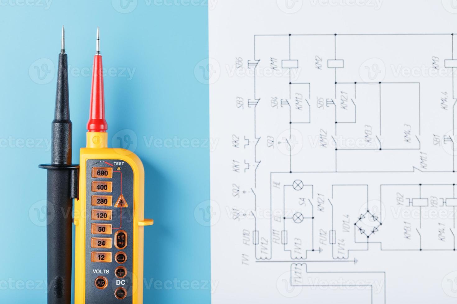 Two-pole voltage indicator with electrical drawings on a blue background. photo