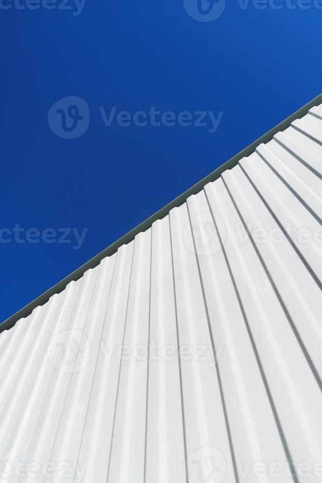 Estructuras metálicas blancas texturizadas en diagonal contra un cielo azul. foto