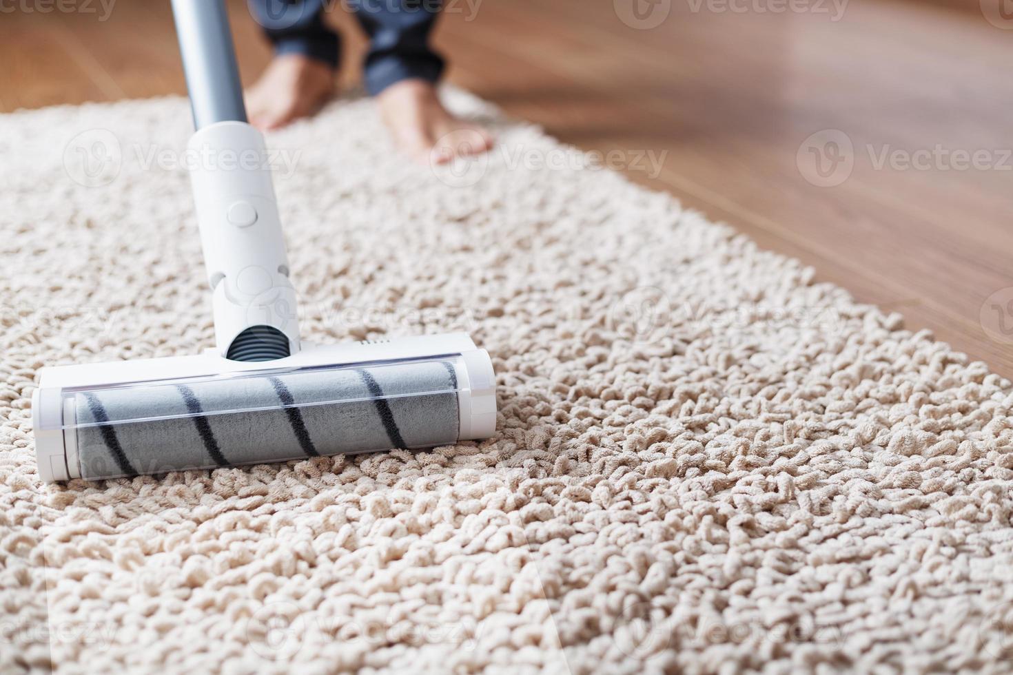 The turbo brush of a cordless vacuum cleaner cleans the carpet in the house With a clean stripe photo