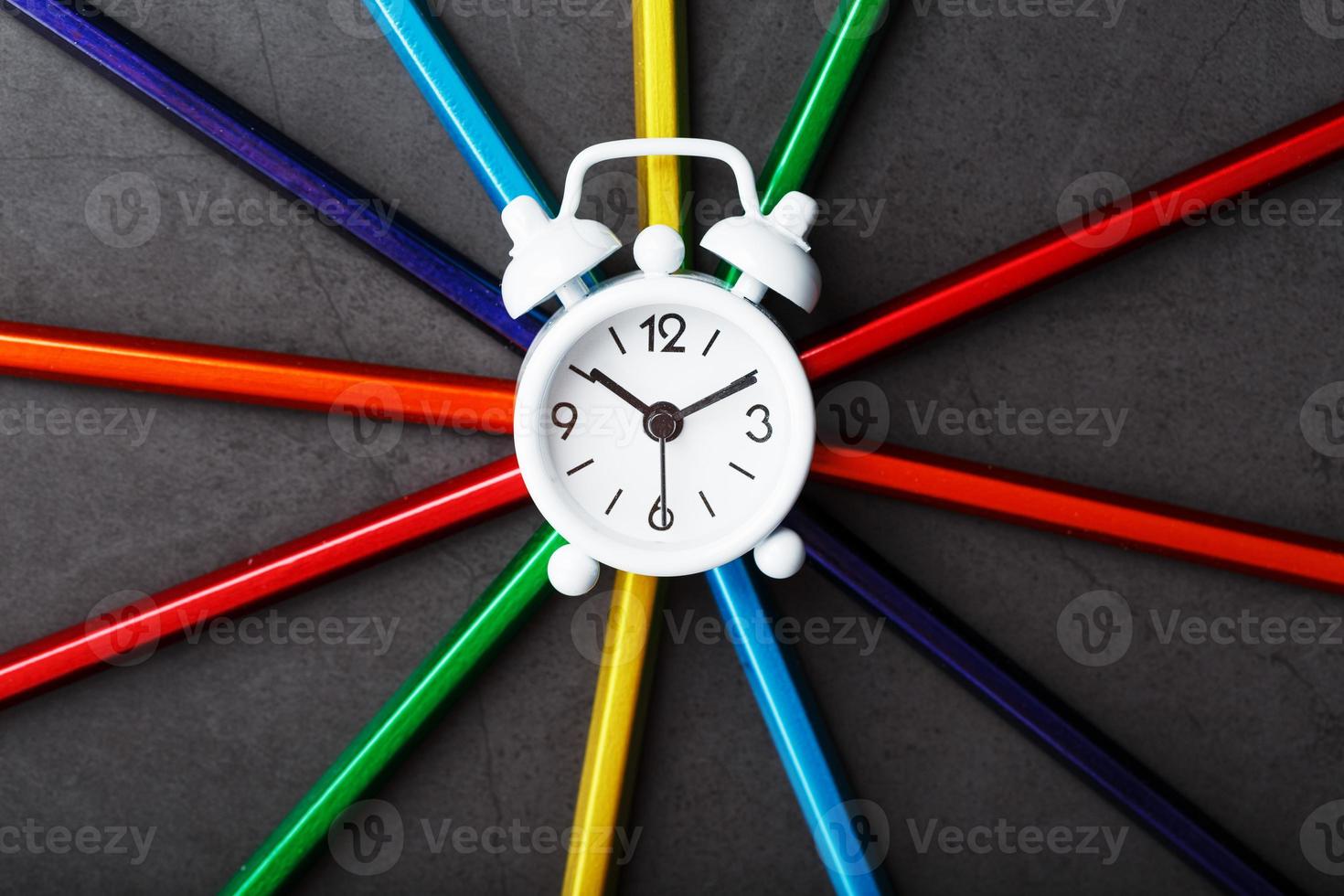 A white alarm clock with colored pencils in the shape of a star photo