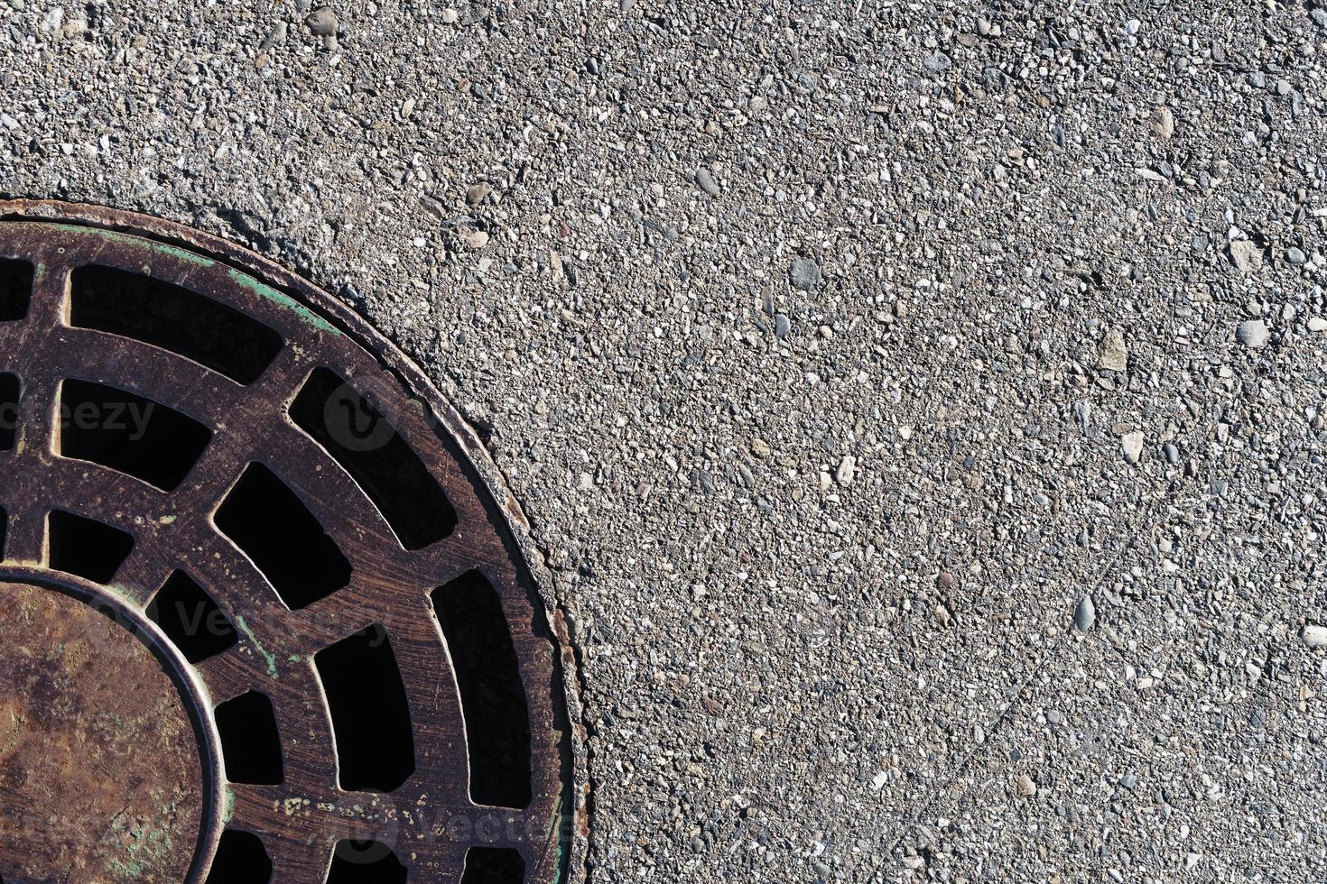 Sewer round hatch with a grate on an asphalt road. photo