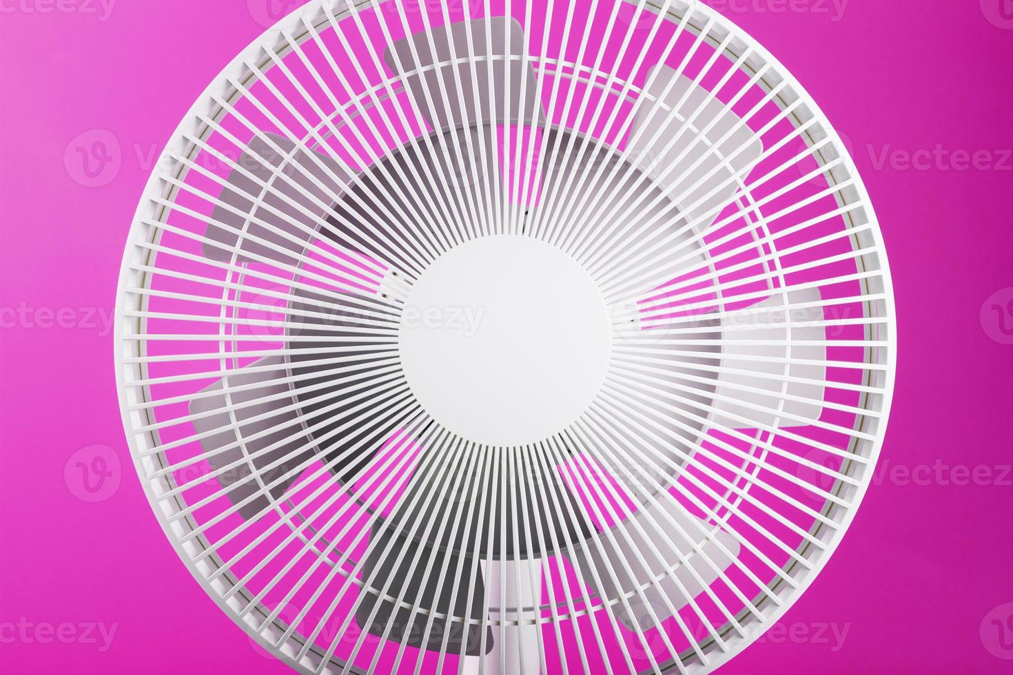 White modern electric fan for cooling the room on a pink background. photo