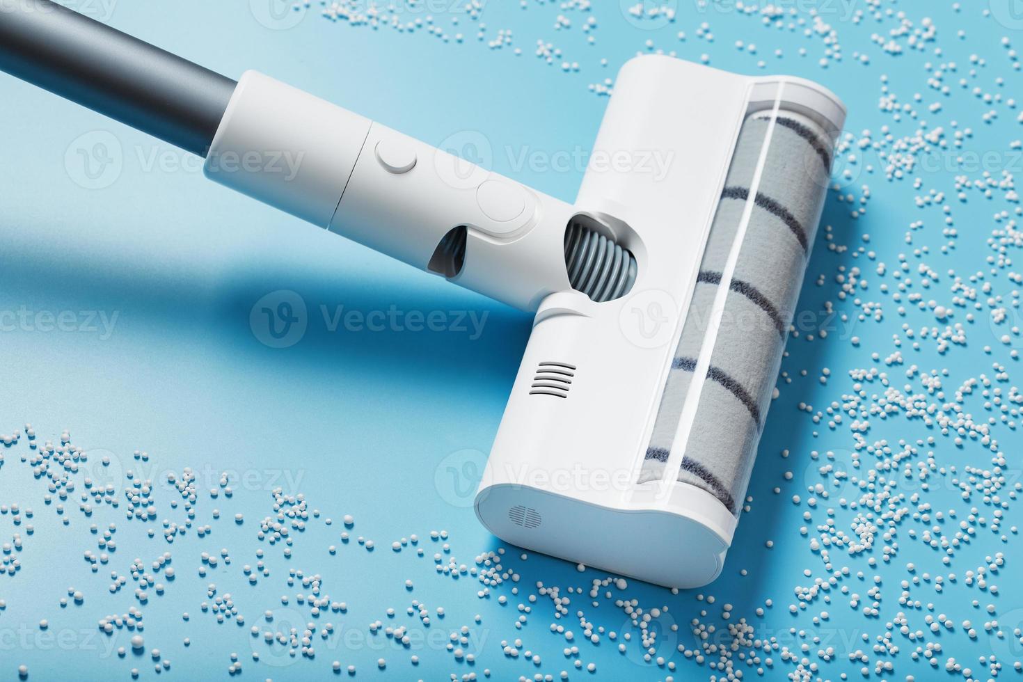 The turbo brush of the vacuum cleaner cleans white balls, top view on a blue background. The concept of cleanliness and cleaning. photo
