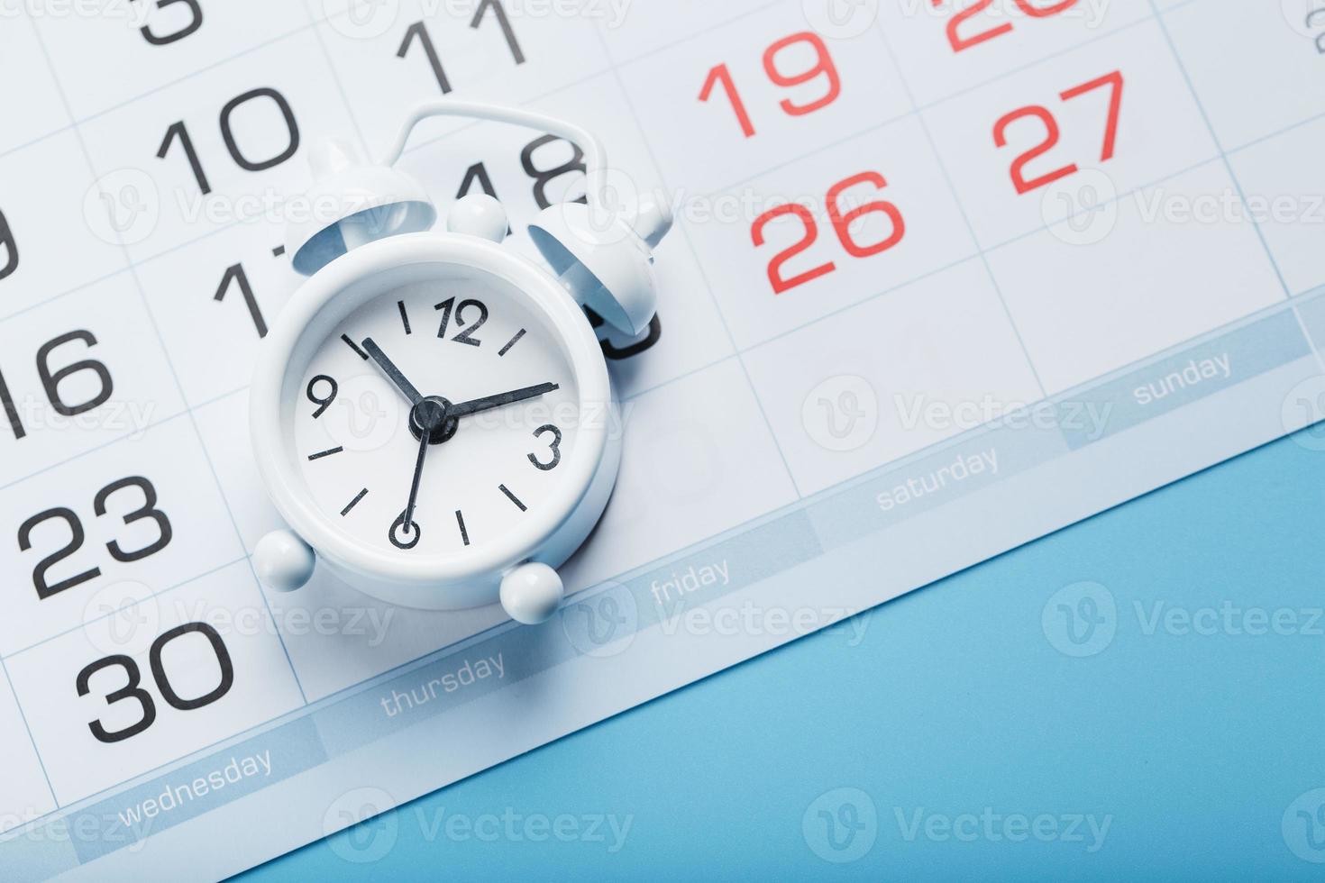 Alarm clock and calendar on a blue background photo