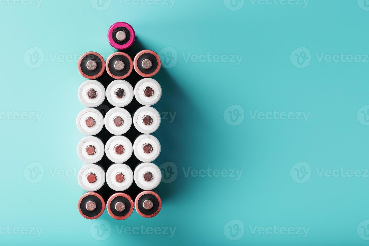 AA batteries are arranged in the form of a large battery on a blue background. photo