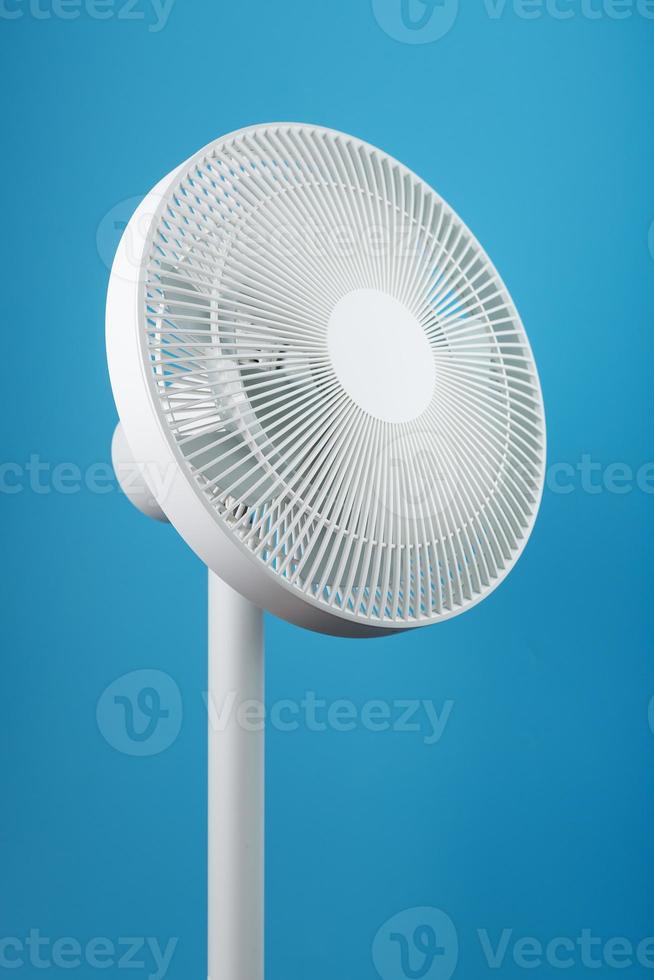 A high-tech white electric fan with a modern design for cooling the room on a blue background photo