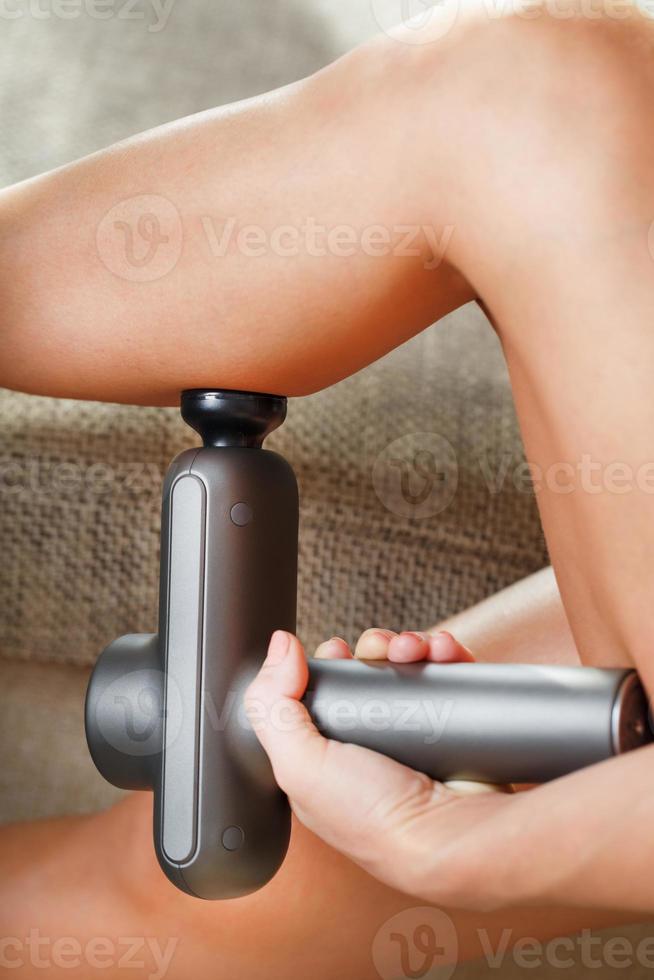 A woman massages her legs with an automatic pistol at home. photo