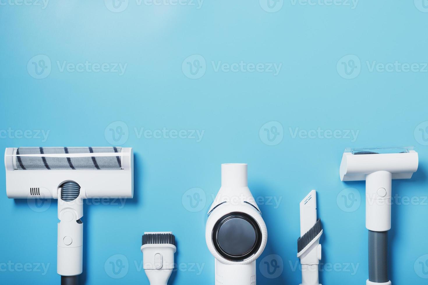 Composition of a set of elements of a wireless white vacuum cleaner on a blue background. Top view photo