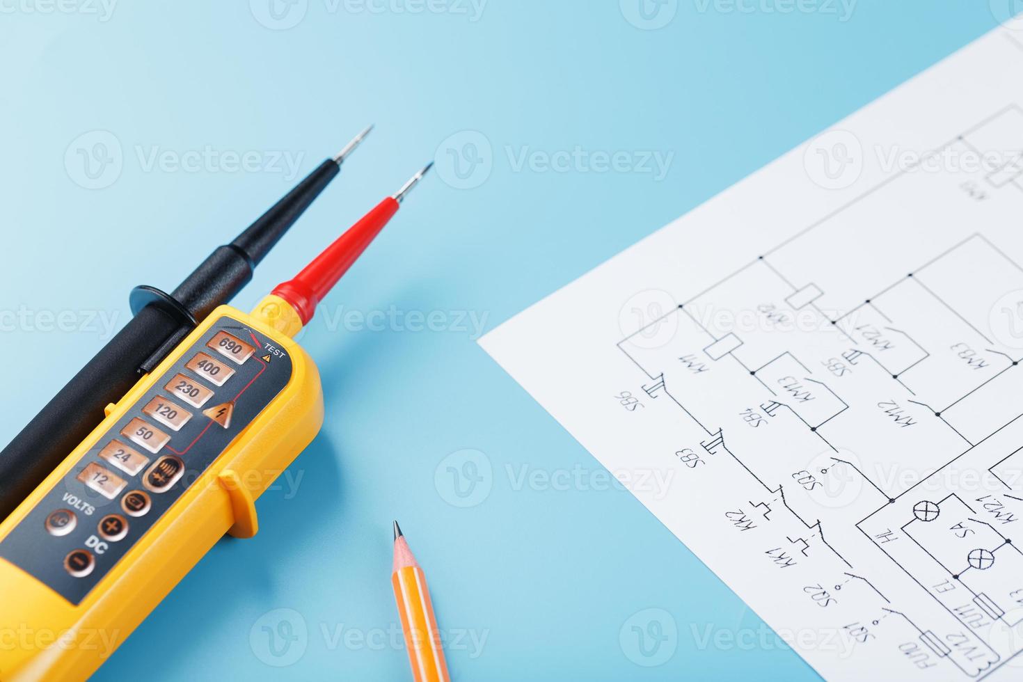 Two-pole voltage indicator with electrical drawings on a blue background. photo