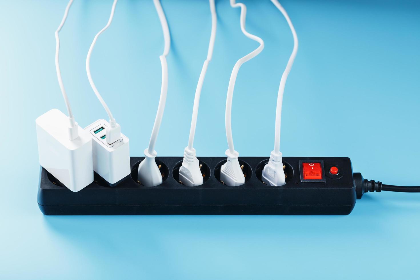 filtro de red eléctrica con enchufes blancos insertados de aparatos eléctricos sobre un fondo azul. foto