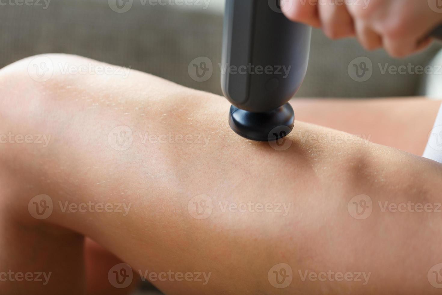 Self-massage of women's legs with a perfecting gun at home. photo