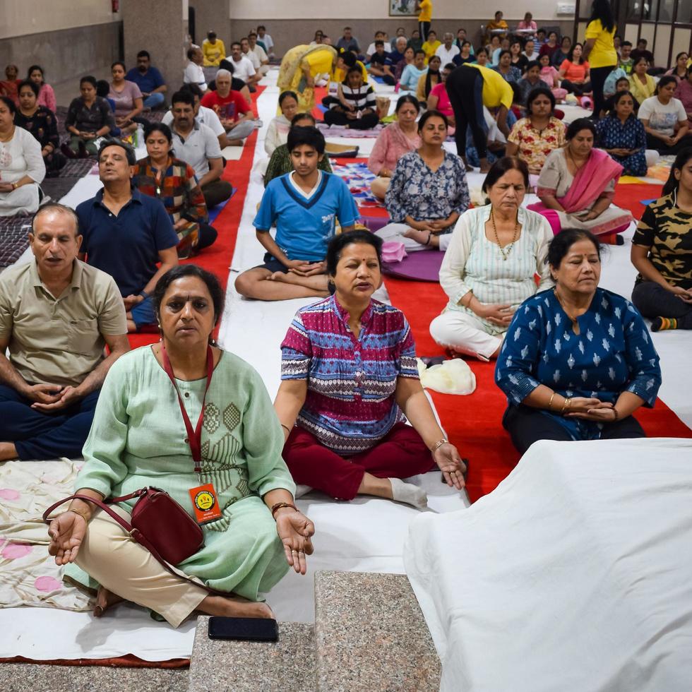 New Delhi, India, June 19 2022 -Group Yoga exercise session for people of different age groups in Balaji Temple, Vivek Vihar, International Yoga Day, Big group of adults attending yoga class in temple photo