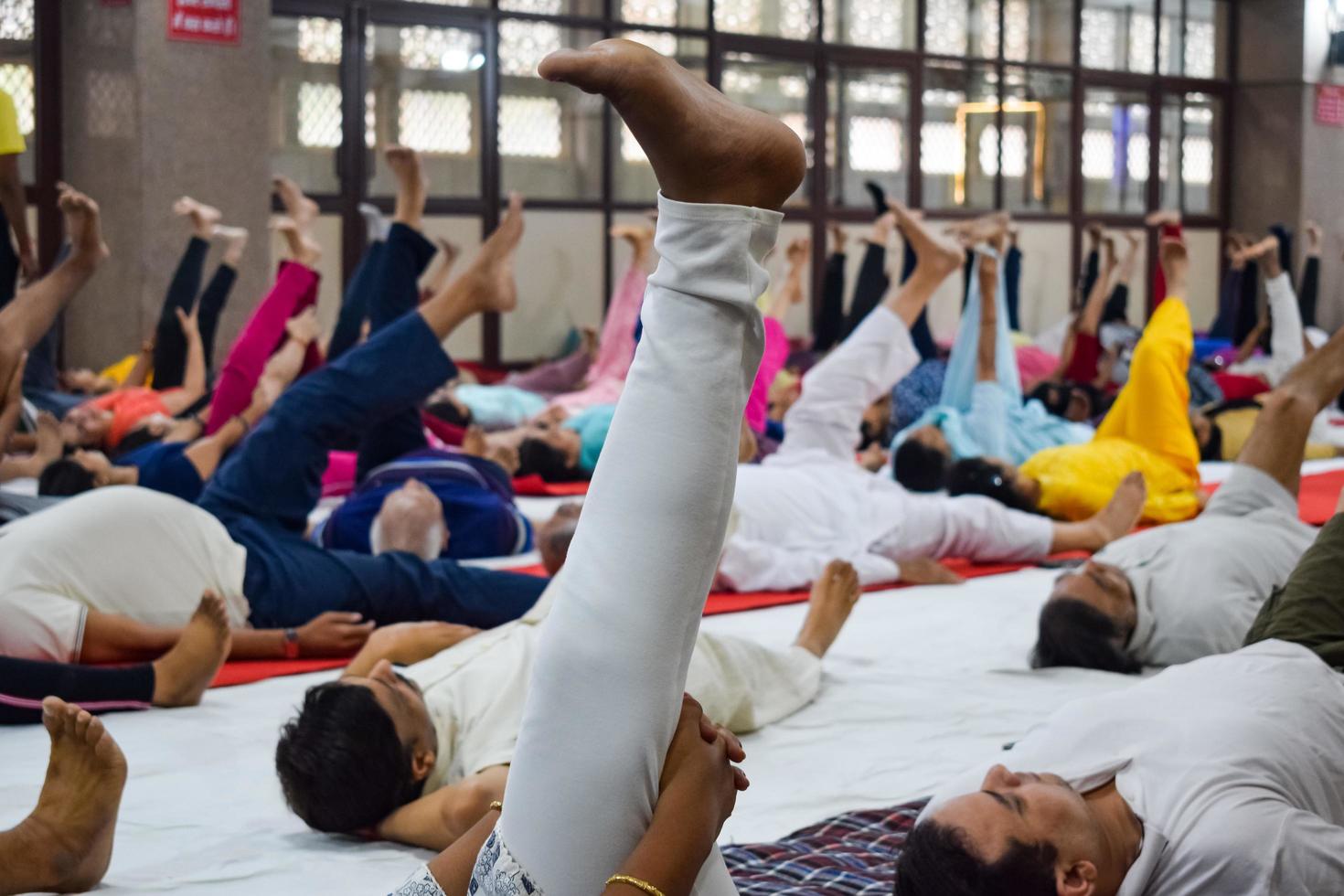 New Delhi, India, June 19 2022 -Group Yoga exercise session for people of different age groups in Balaji Temple, Vivek Vihar, International Yoga Day, Big group of adults attending yoga class in temple photo